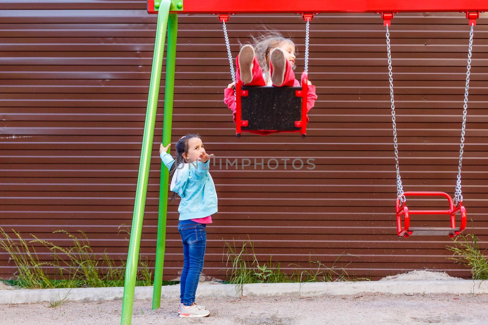 Young child on swing in playground outdoors by Andelov13