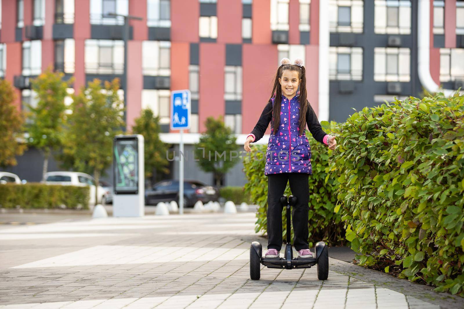 Happylittle girl standing on electric scooter outdoor by Andelov13
