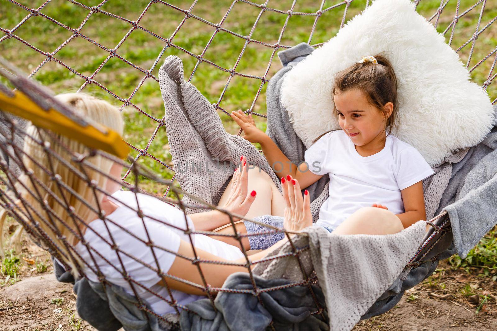 loving family spends time together in summer time enjoy the little things. slow life. mom and little daughter relax in a hammock in the summer in the garden by Andelov13