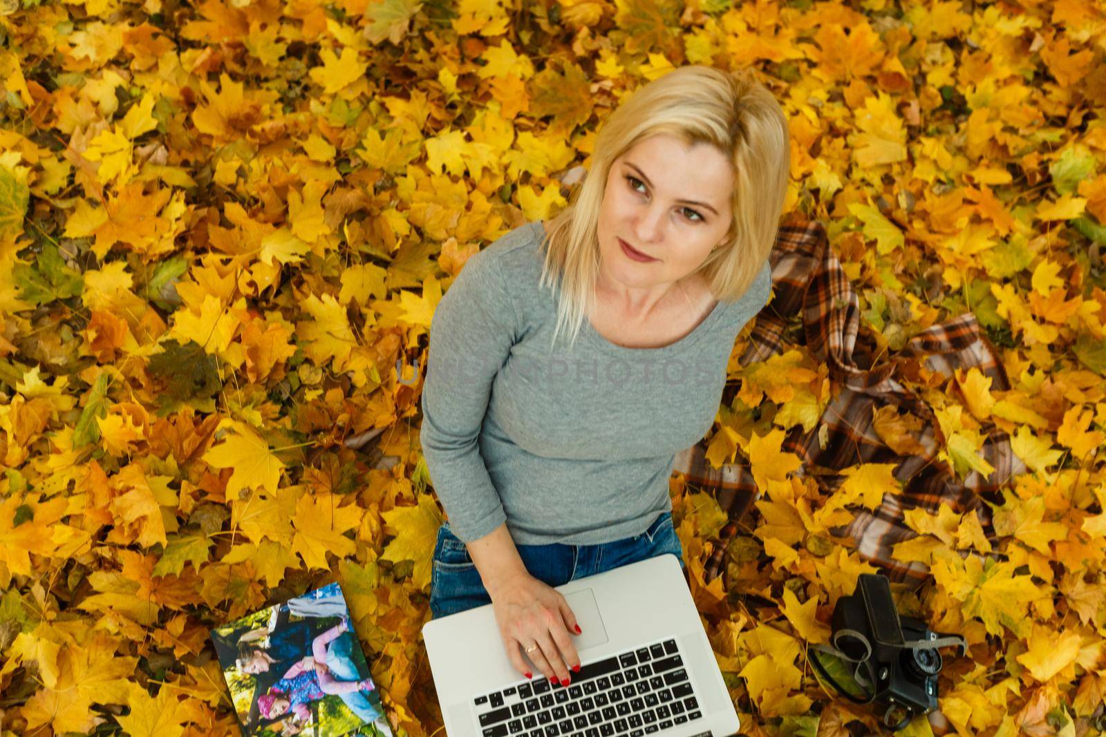 woman with laptop and photo book in autumn.