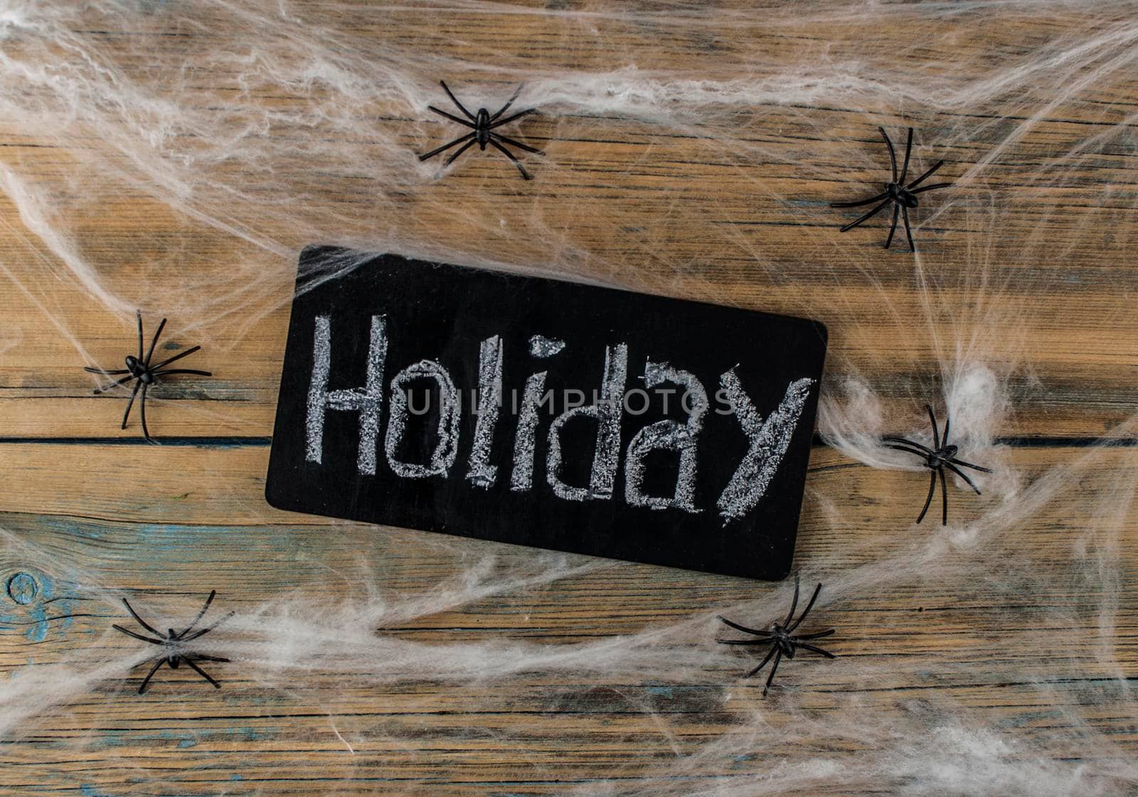 cobweb or spider web and black board with handwritten text HOLIDAY on wooden texture background wall by inxti