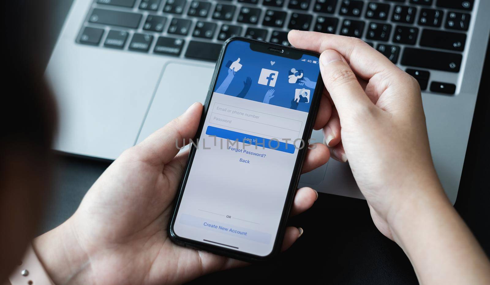 CHIANG MAI ,THAILAND - APR 10, 2021 : Woman hand holding iPhone 6S to use facebook with new login screen.Facebook is a largest social network and most popular social networking site in the world.