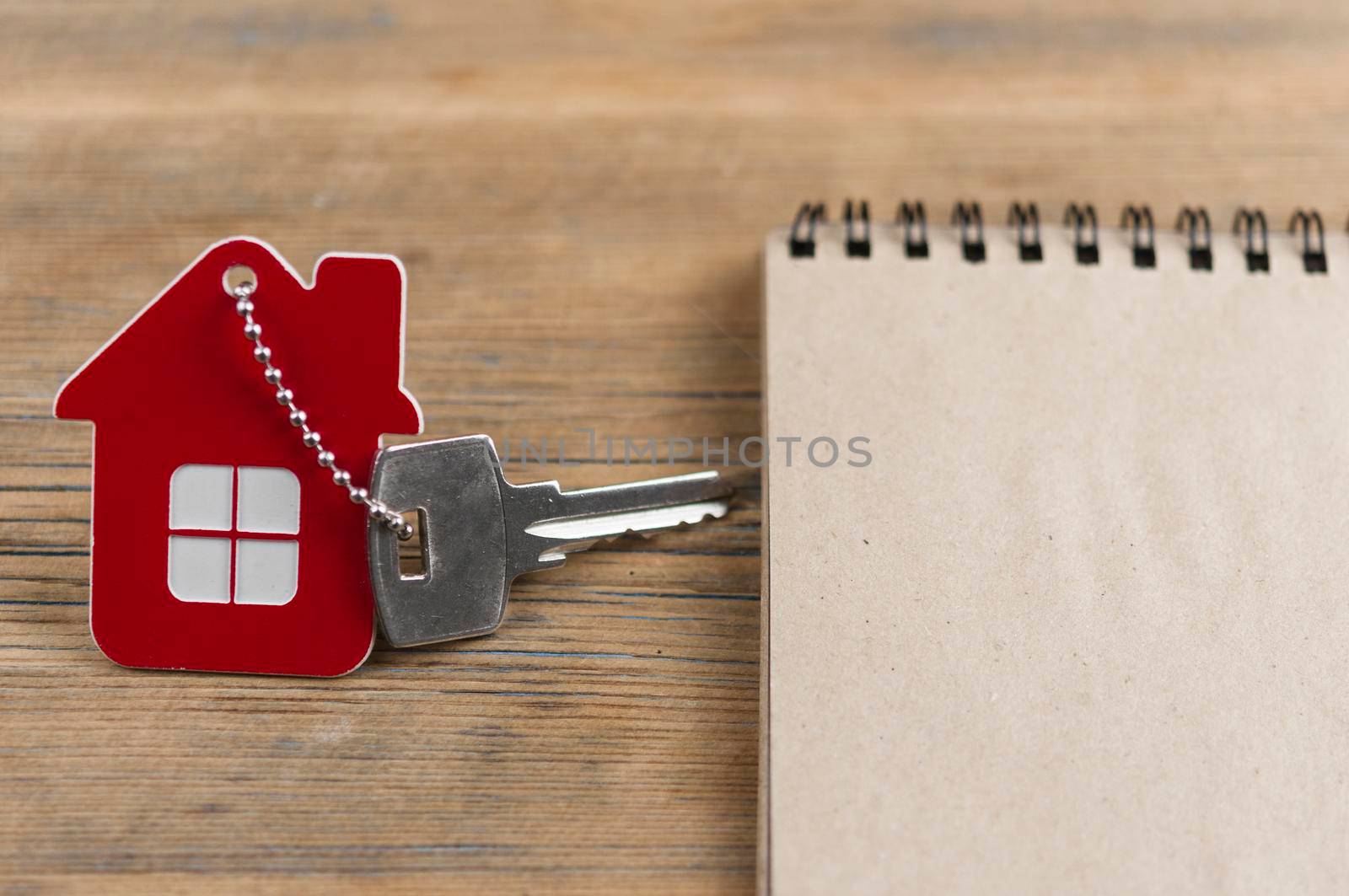 House keys with house shaped keychain on wooden background