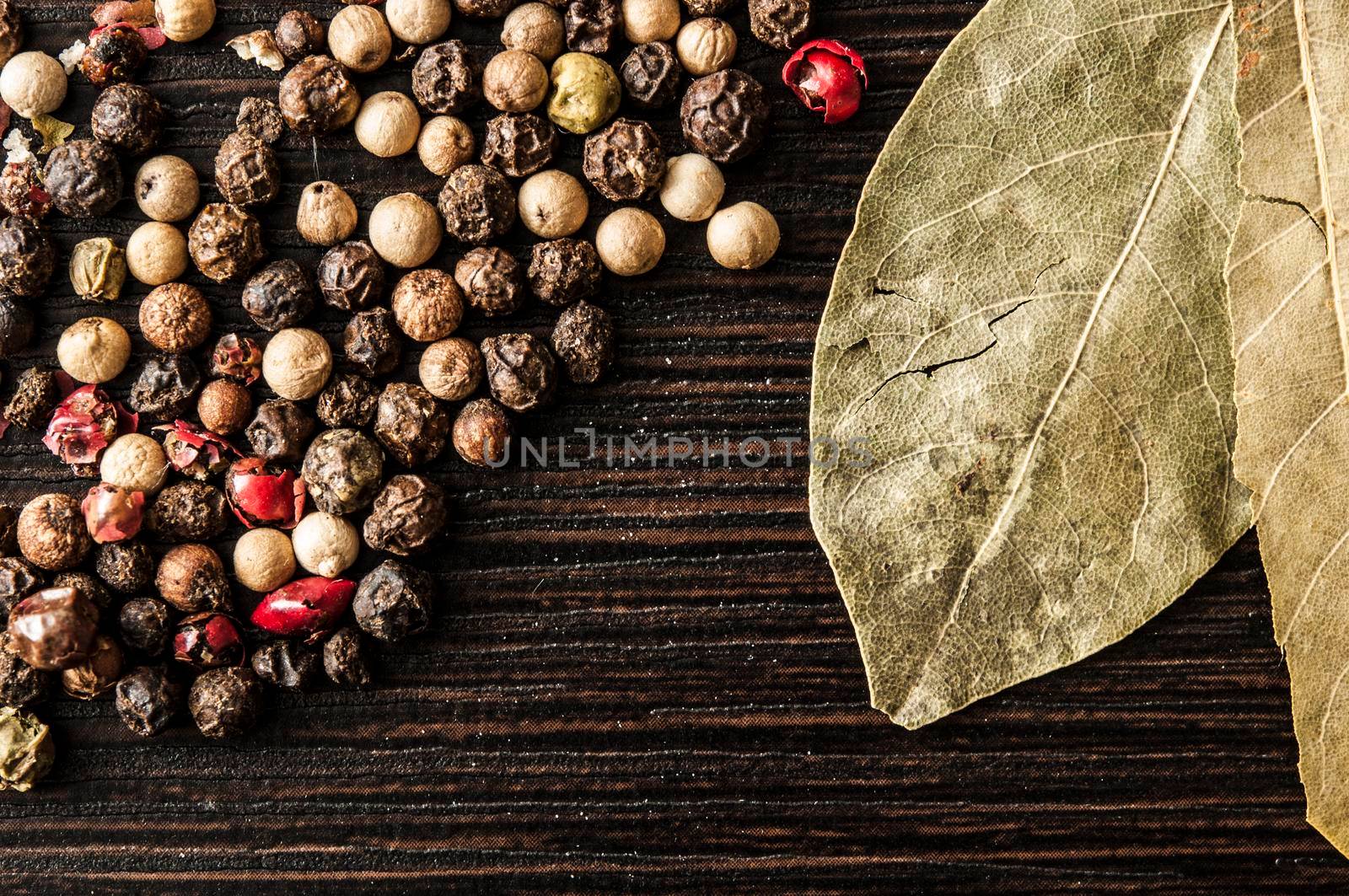 Spice. Bay leaves and pepper mix on a dark wooden table. 