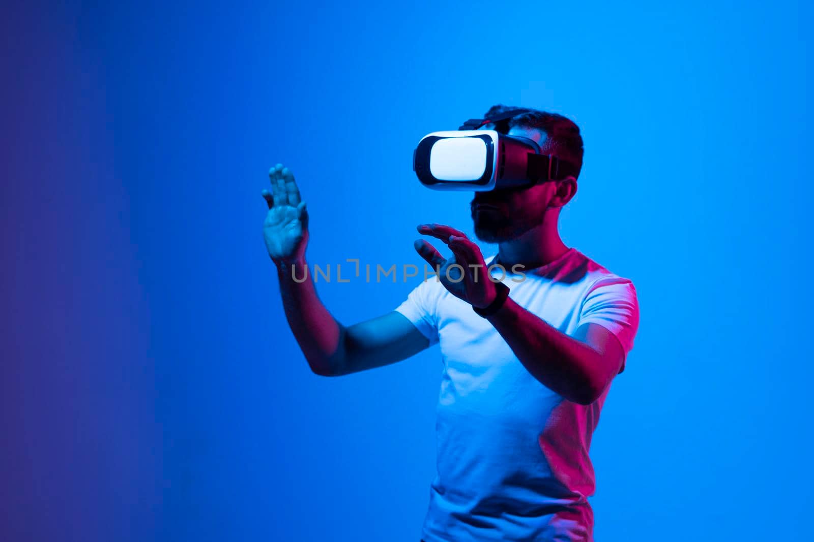 Bearded ambitious modern male working in VR glasses while pointing with finger on a subject in virtual reality