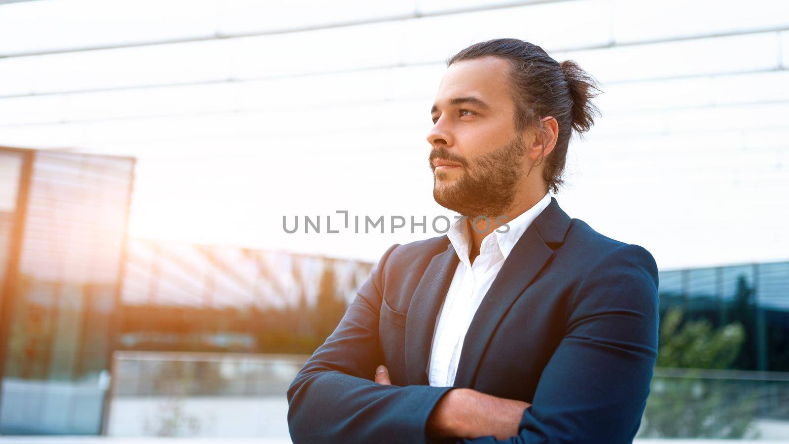 Successful businessman suit with beard standing in front of office glass building arm crossed confidently looking away. Hispanic male business person side view portrait. Web banner, Free space