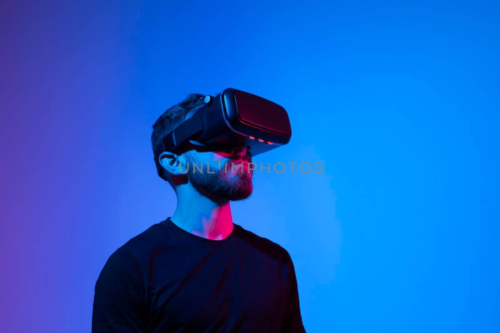 Man a gamer in black t-shirt in modern wireless glasses of virtual reality plays a video game in a dark room