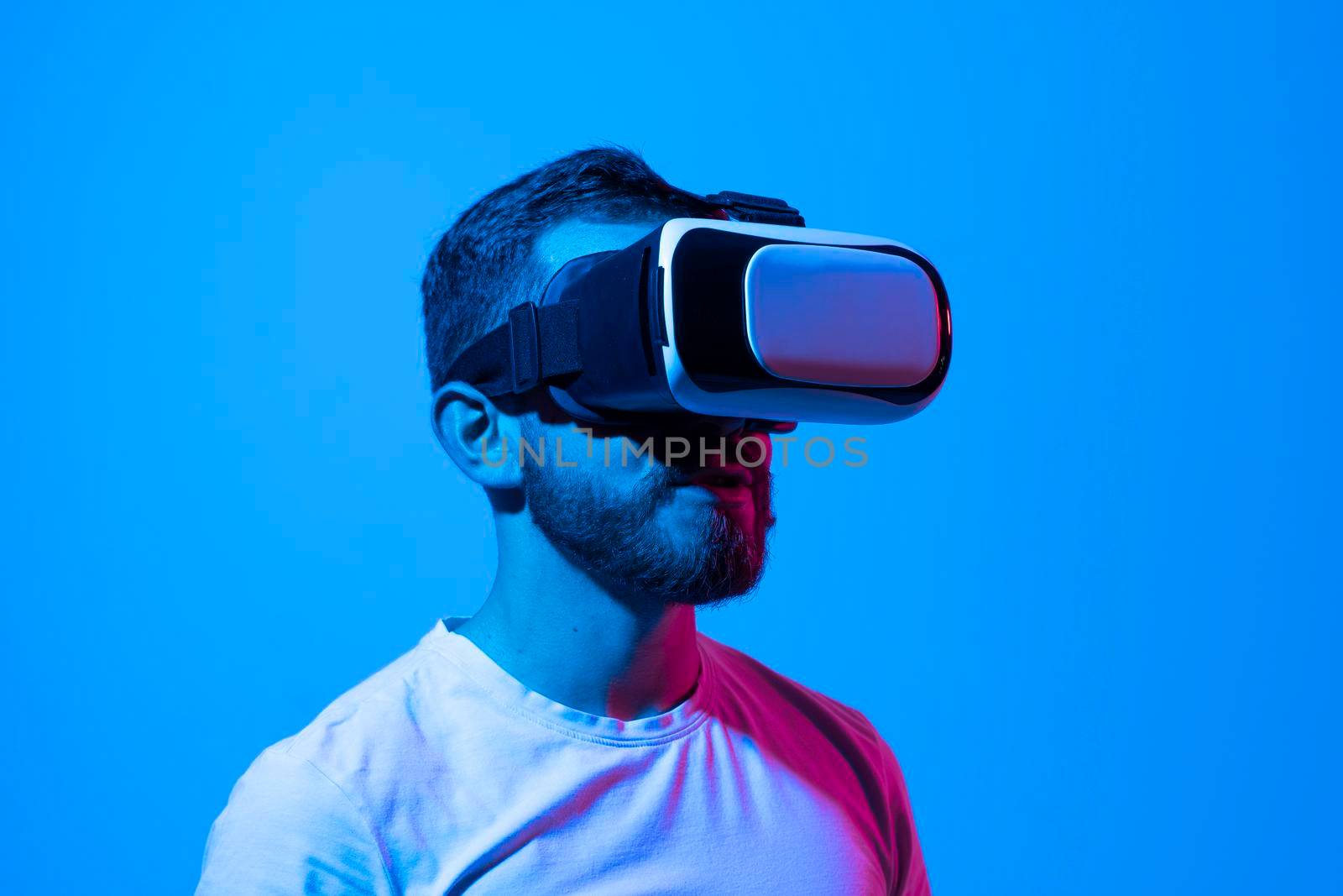 Casual bearded man trying VR headset and exploring another world in neon lights