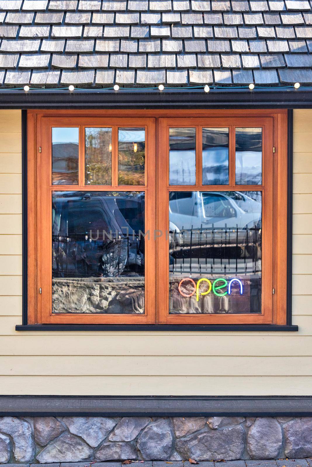 Street cafe window with colour light sign Open inside.