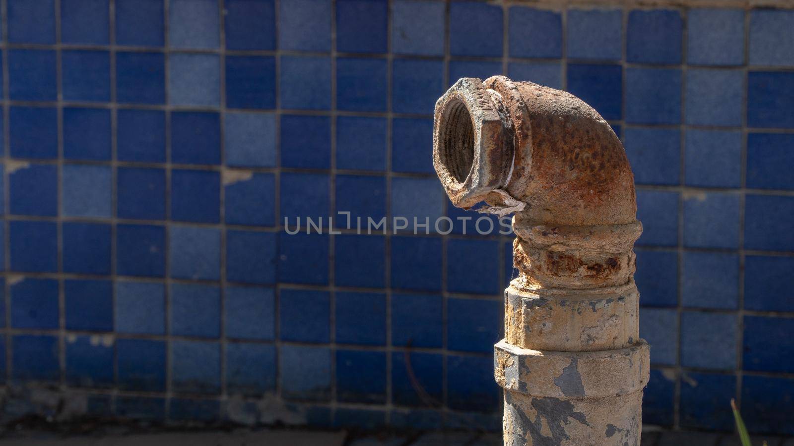 Metal rusty pipe on the background of blue facing tiles by voktybre