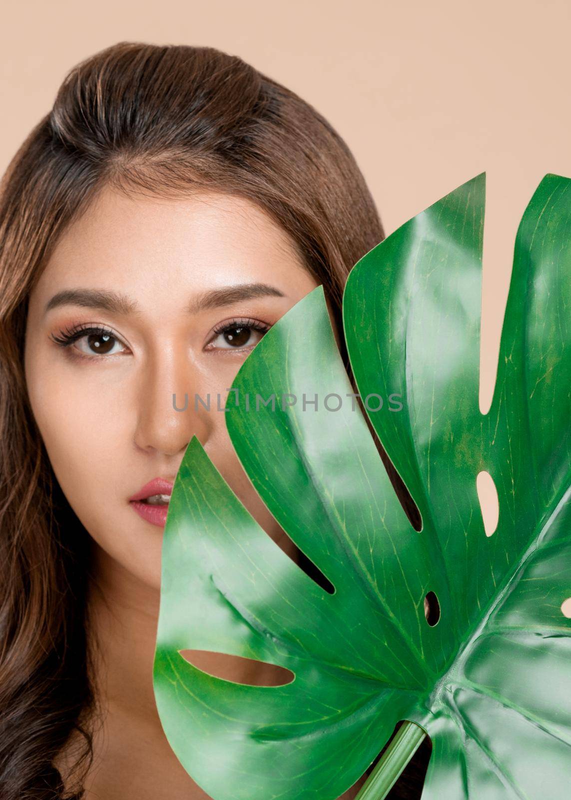 Closeup young ardent woman with healthy skin holding green leaf near her face. by biancoblue