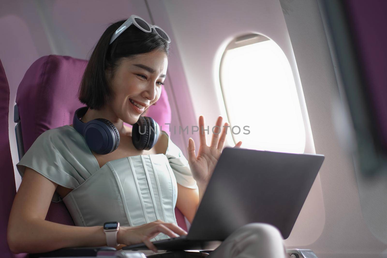 Asian young woman using laptop sitting near windows at first class on airplane during flight,Traveling and Business concept.