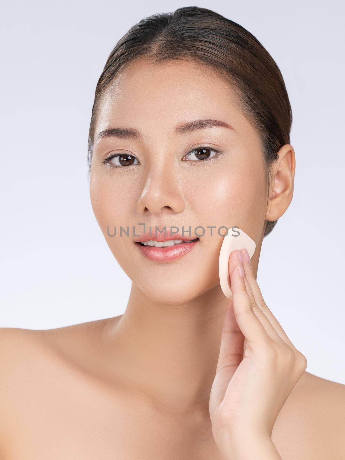 Gorgeous woman applying her cheek with dry powder. Portrait of younger with perfect makeup and healthy skin concept.