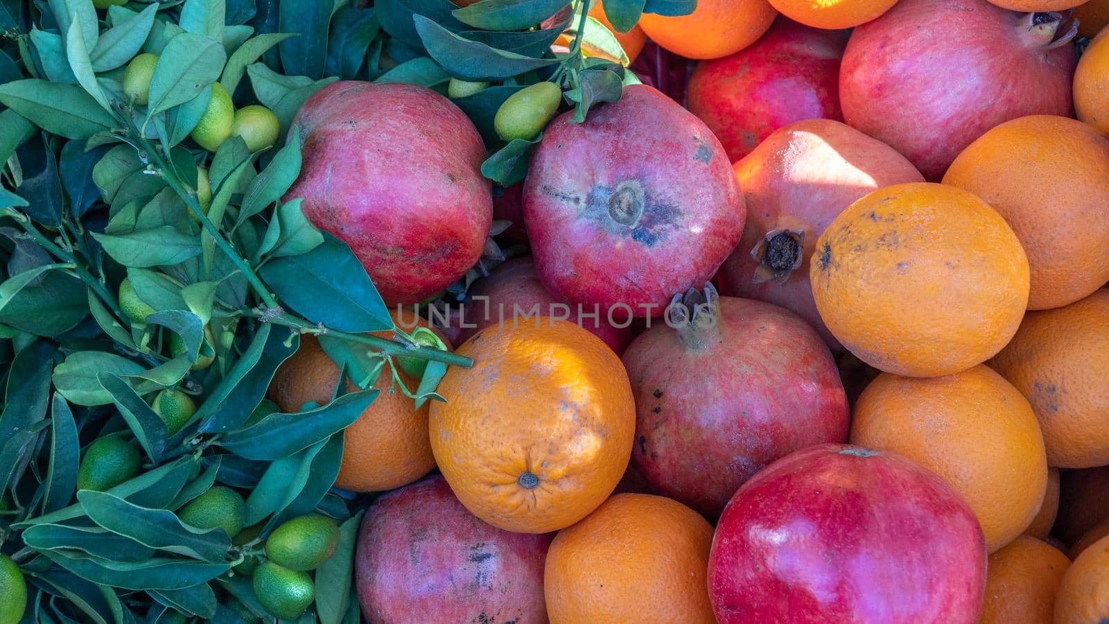 Fruity background of pomegranates, oranges and olives on a branch by voktybre
