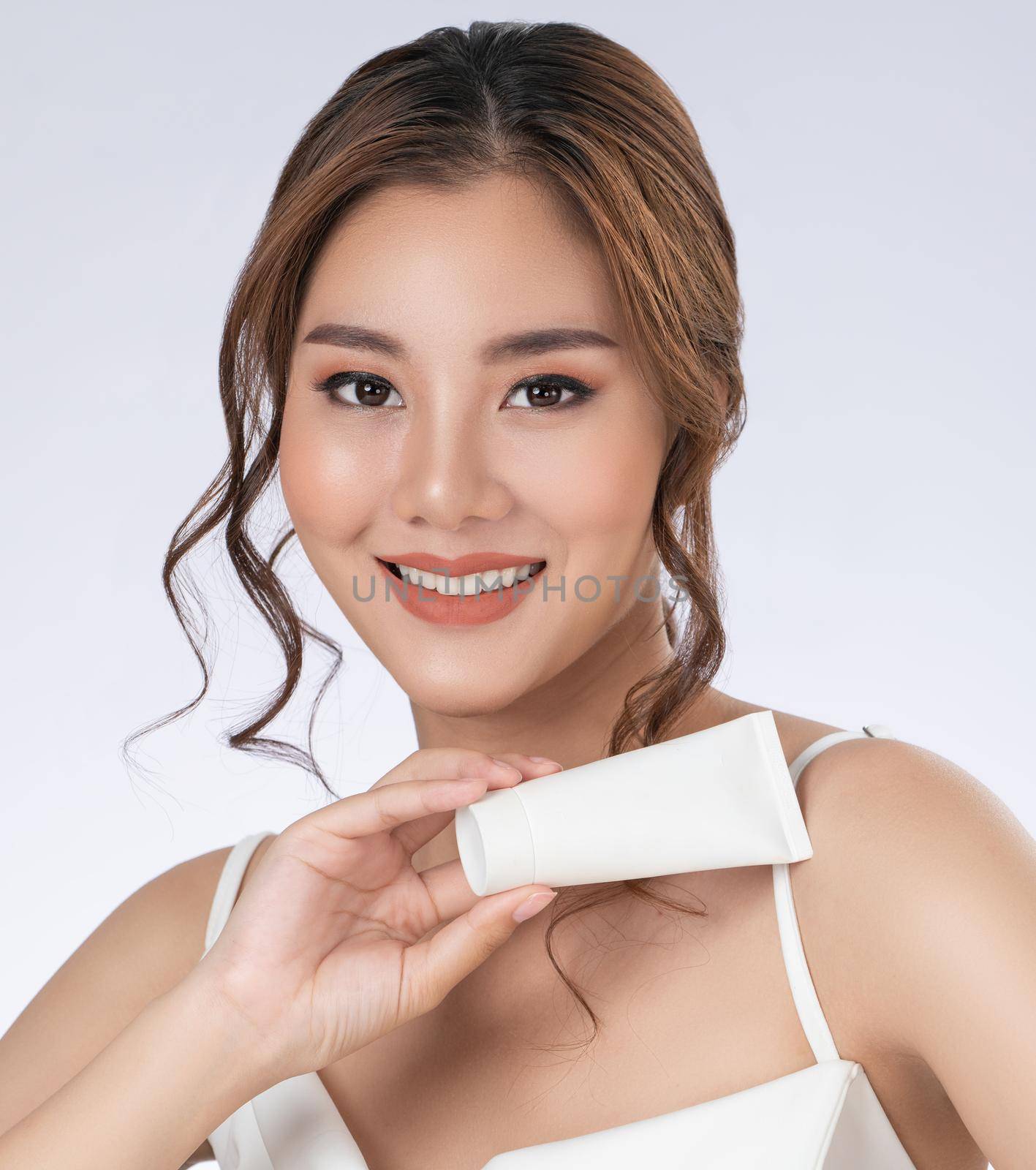 Gorgeous woman with makeup smiling holding mockup product for advertising. by biancoblue