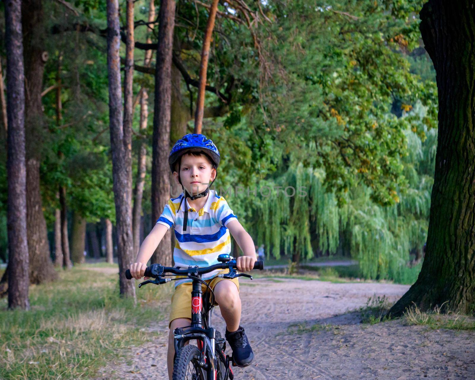 Portrait of happy toddler child boy riding on bike with helmet. He rides from a small hill, through a sandy forest path. Sport concept: kids ride bicycle first bike active toddler kid by Kobysh