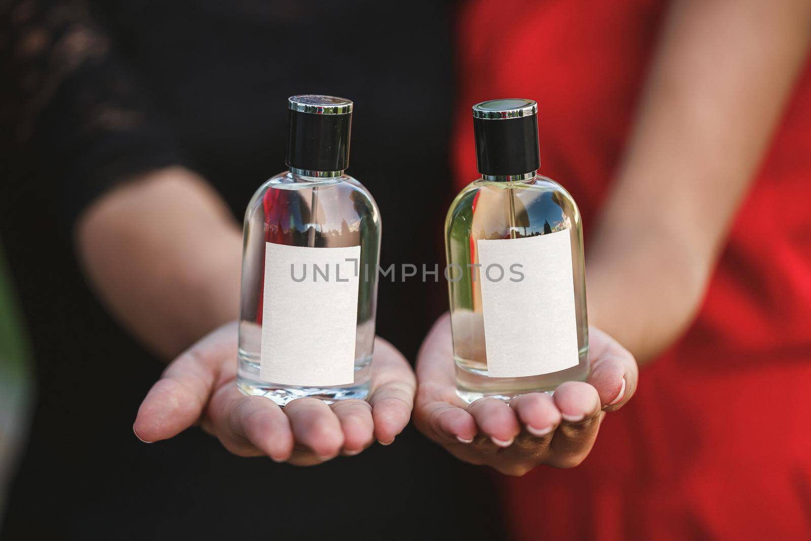 Perfume bottle of a female hand. Young stylish woman holding a bottle of perfume. Fashionable perfume in the hands of women. Girl spraying perfume. Beautiful female hands. Perfumes for women