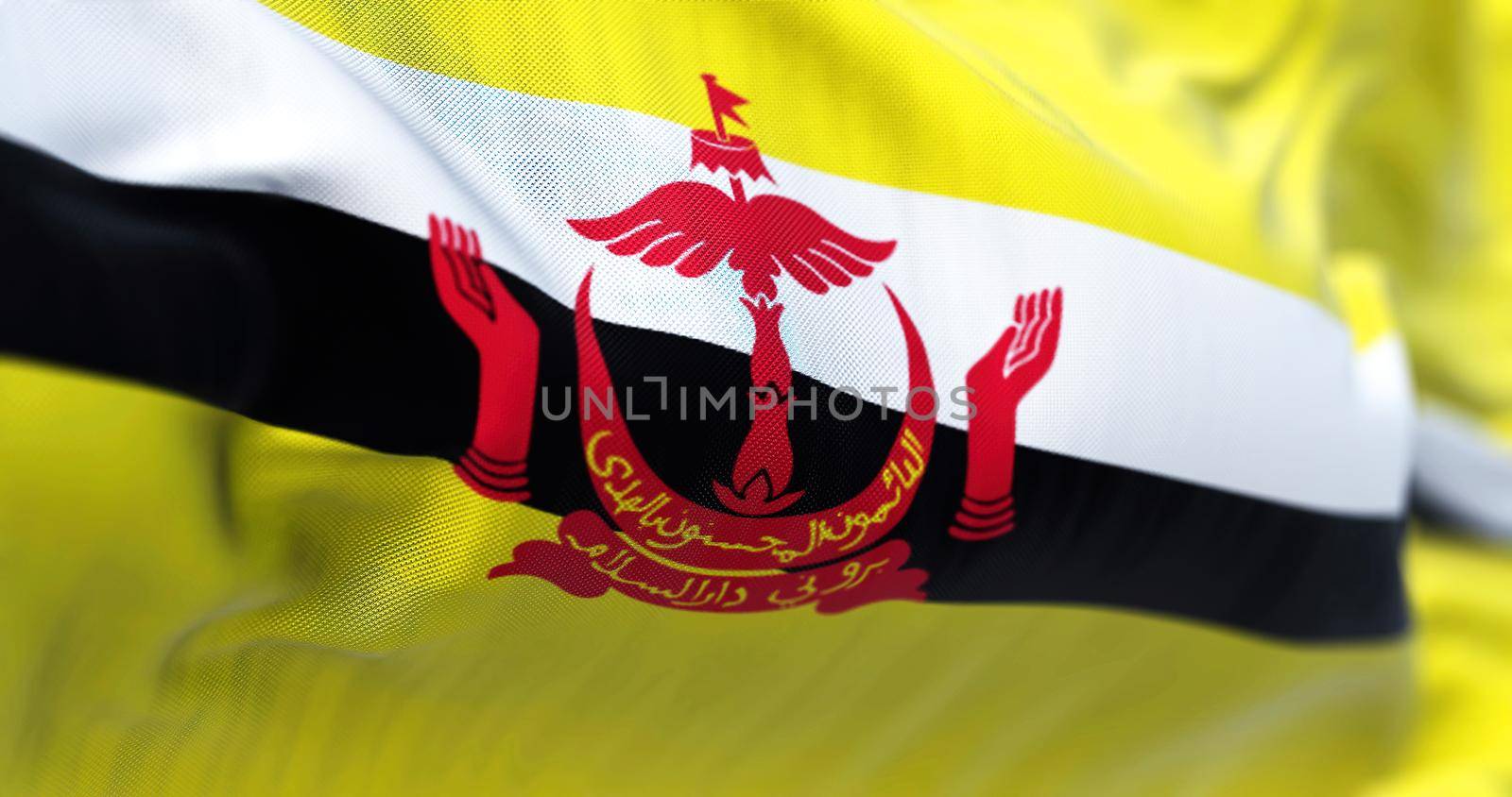 Close-up view of the Brunei national flag waving in the wind. Brunei Darussalam is a country in the Southeast Asia. Fabric textured background. Selective focus