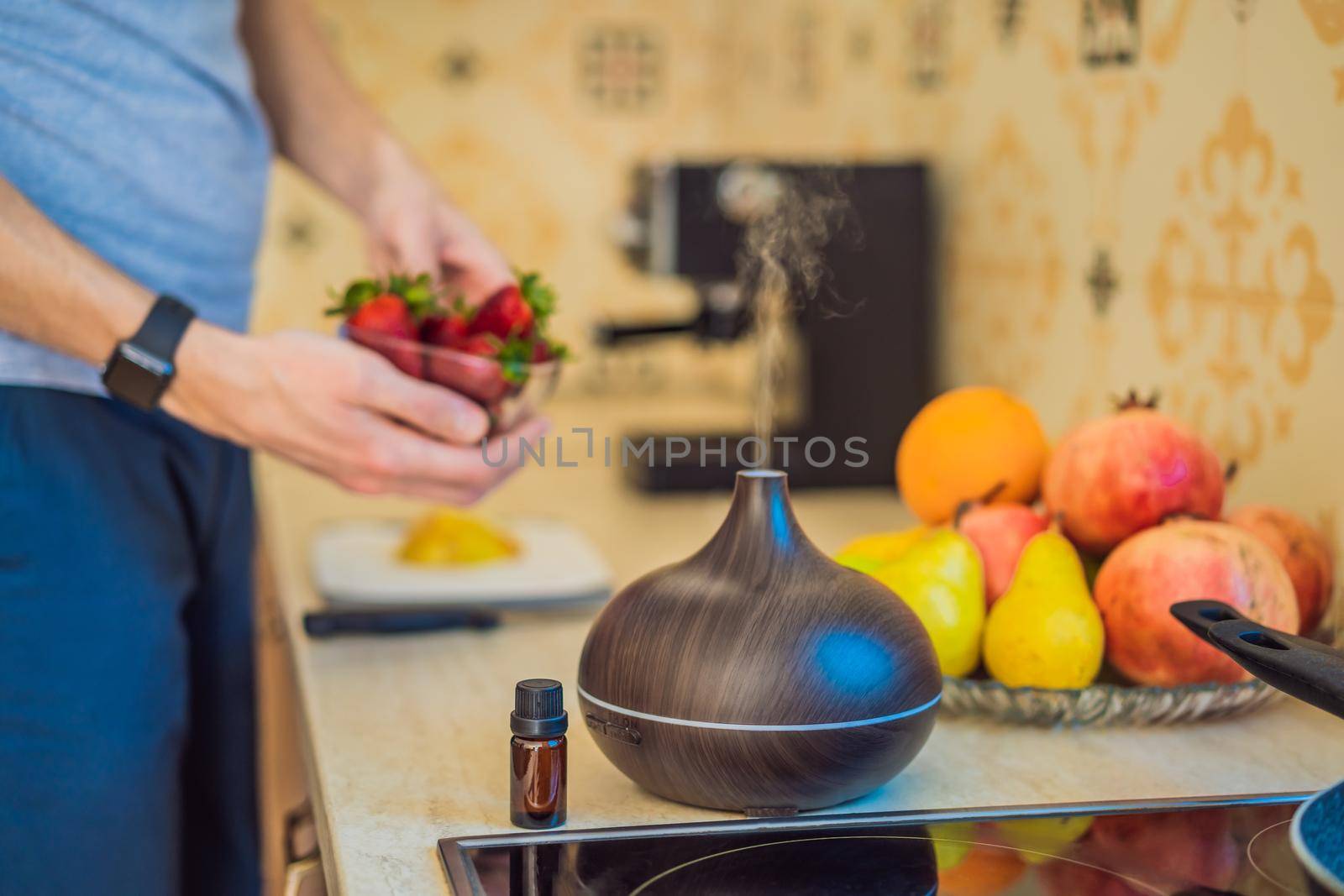 A man prepares food next to an aroma diffuser. cook cuts ripe red peppers in the kitchen. Cooking fresh, ripe, bell pepper salad for guests. Summer fresh vegetable salad.