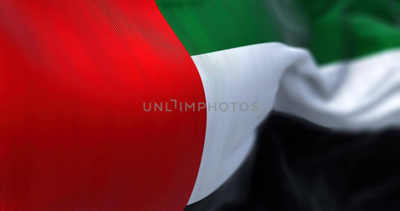 Close-up view of the United Arab Emirates national flag waving in the wind. The Emirates is a country in Western Asia. Fabric textured background. Selective focus