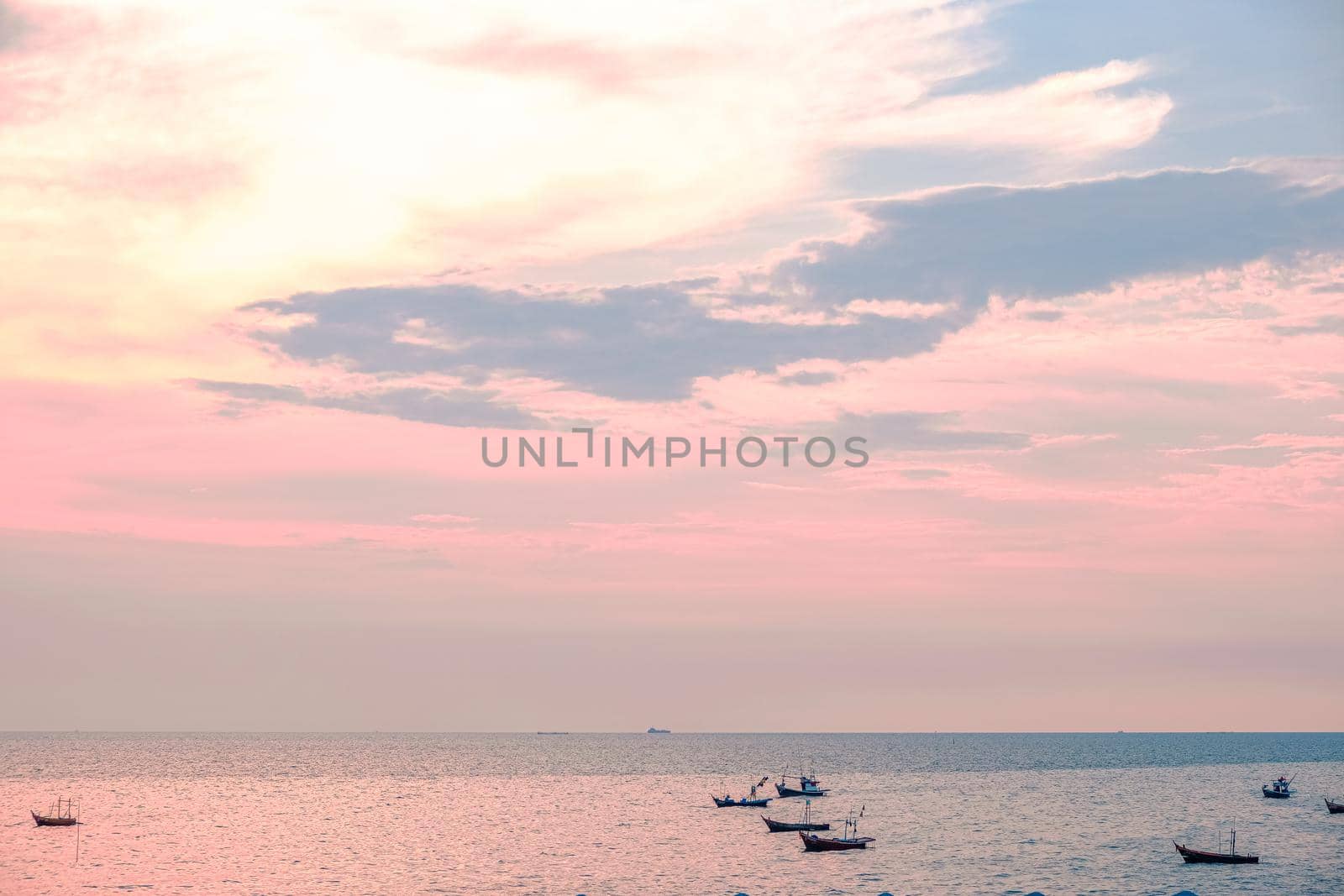 Beautiful sunrise on sea background with tropical wooden fishing boat pink tone