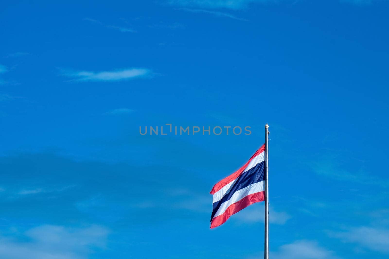 National Flag of Thailand on pole against nature blue sky background.
