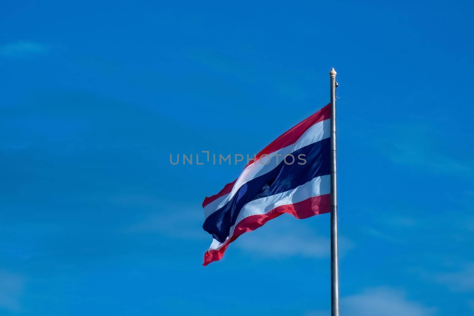 National Flag of Thailand on pole against nature blue sky background. by Petrichor