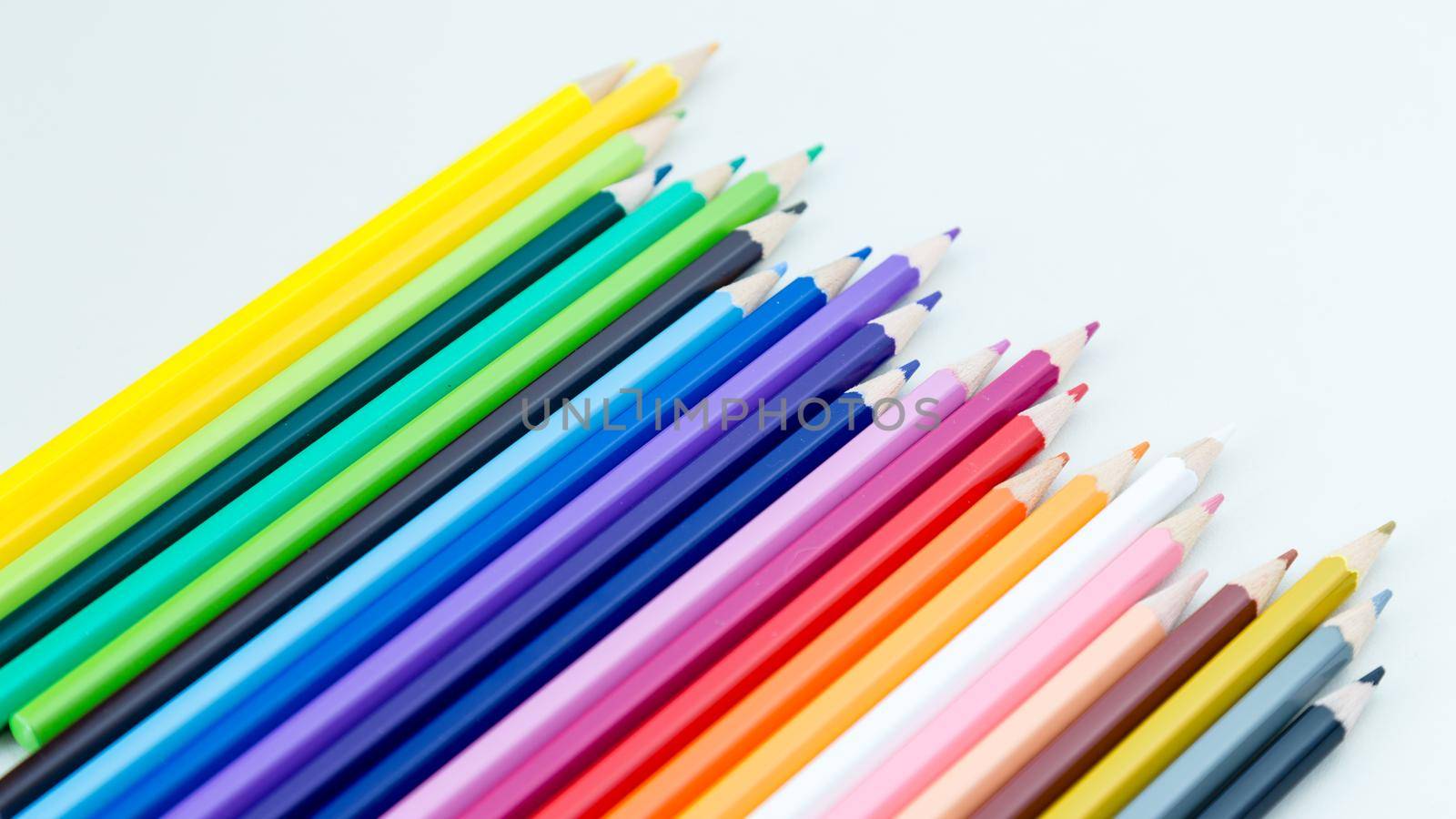 Colored pencil crayons in a row on white background