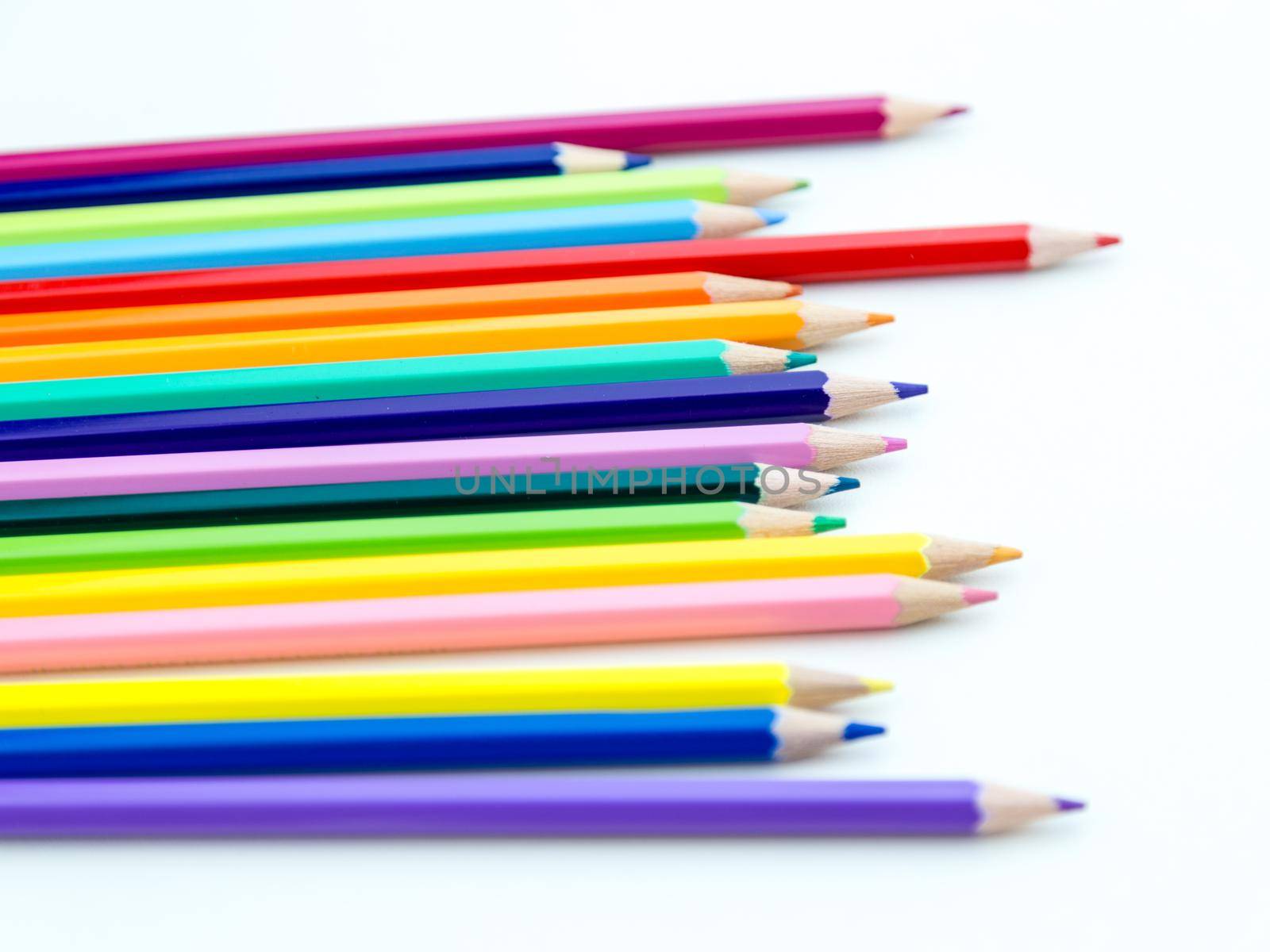 Colored pencil crayons in a row on white background