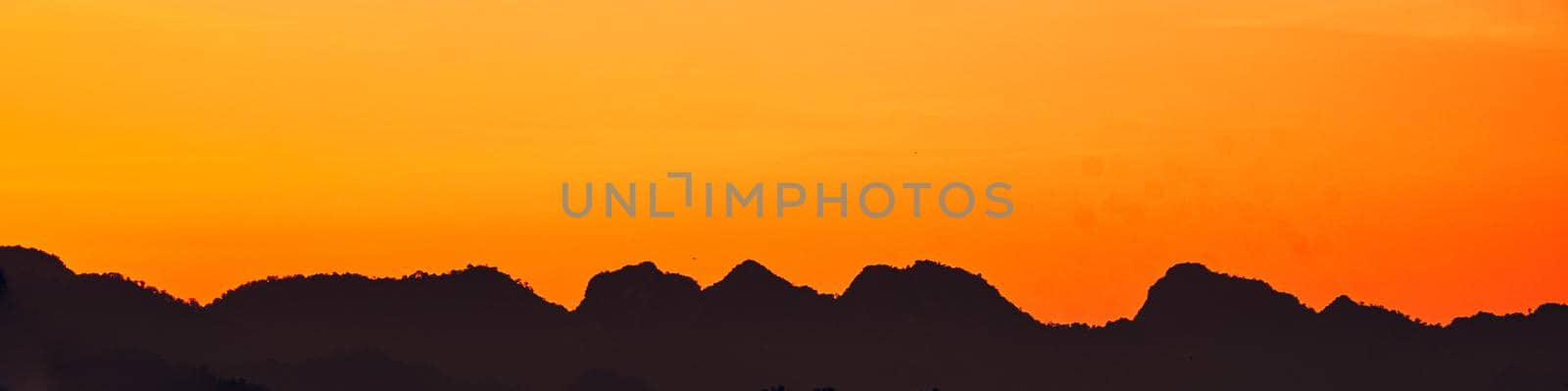 Dramatic  sunset landscape with orange sky, silhouettes of mountains nature background.