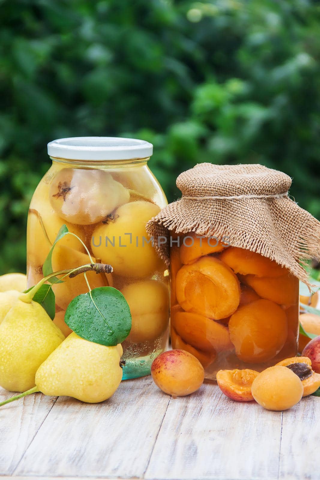Preserved house pears, apricots and jam with blackberries in jars. Selective focus. by yanadjana