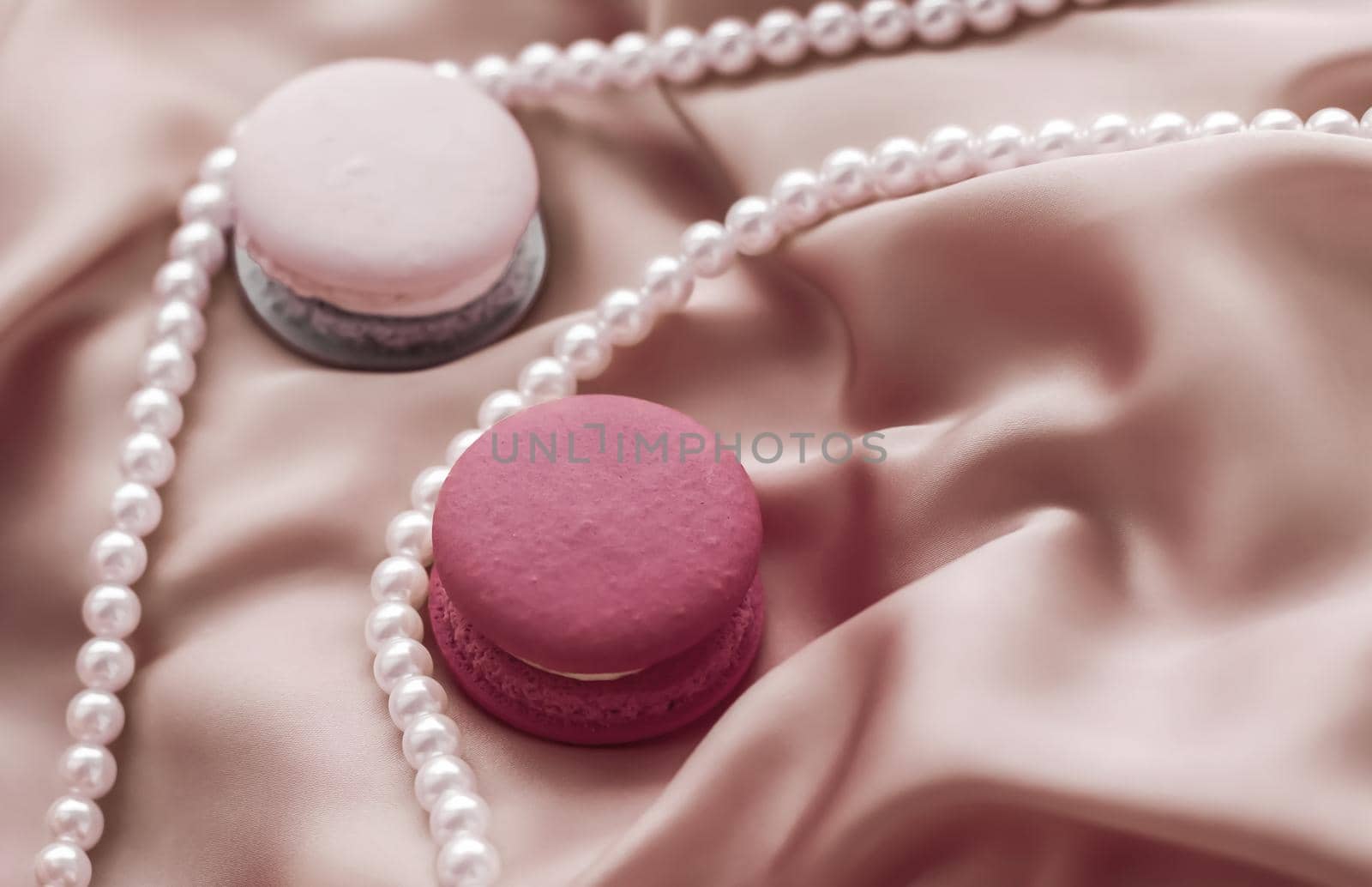 Girly, bakery and branding concept - Sweet macaroons and pearls jewellery on silk background, parisian chic jewelry, French dessert food and cake macaron for luxury confectionery brand, holiday gift