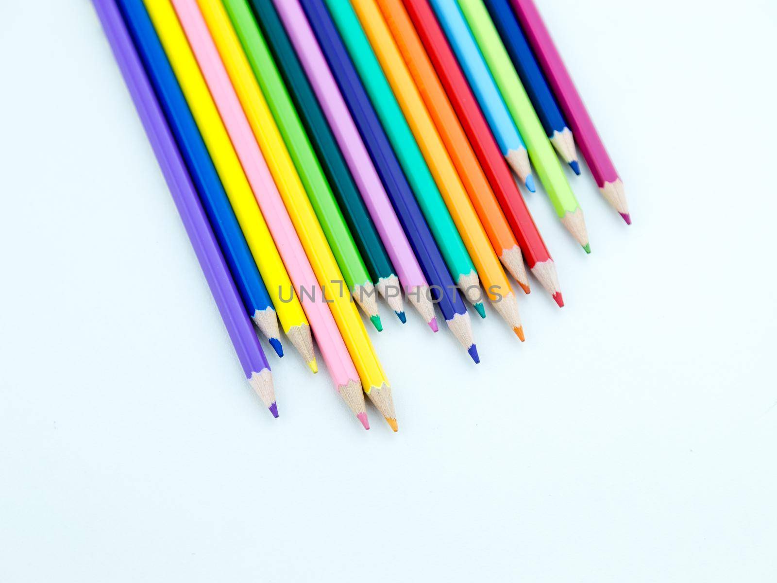 Colored pencil crayons in a row on white background