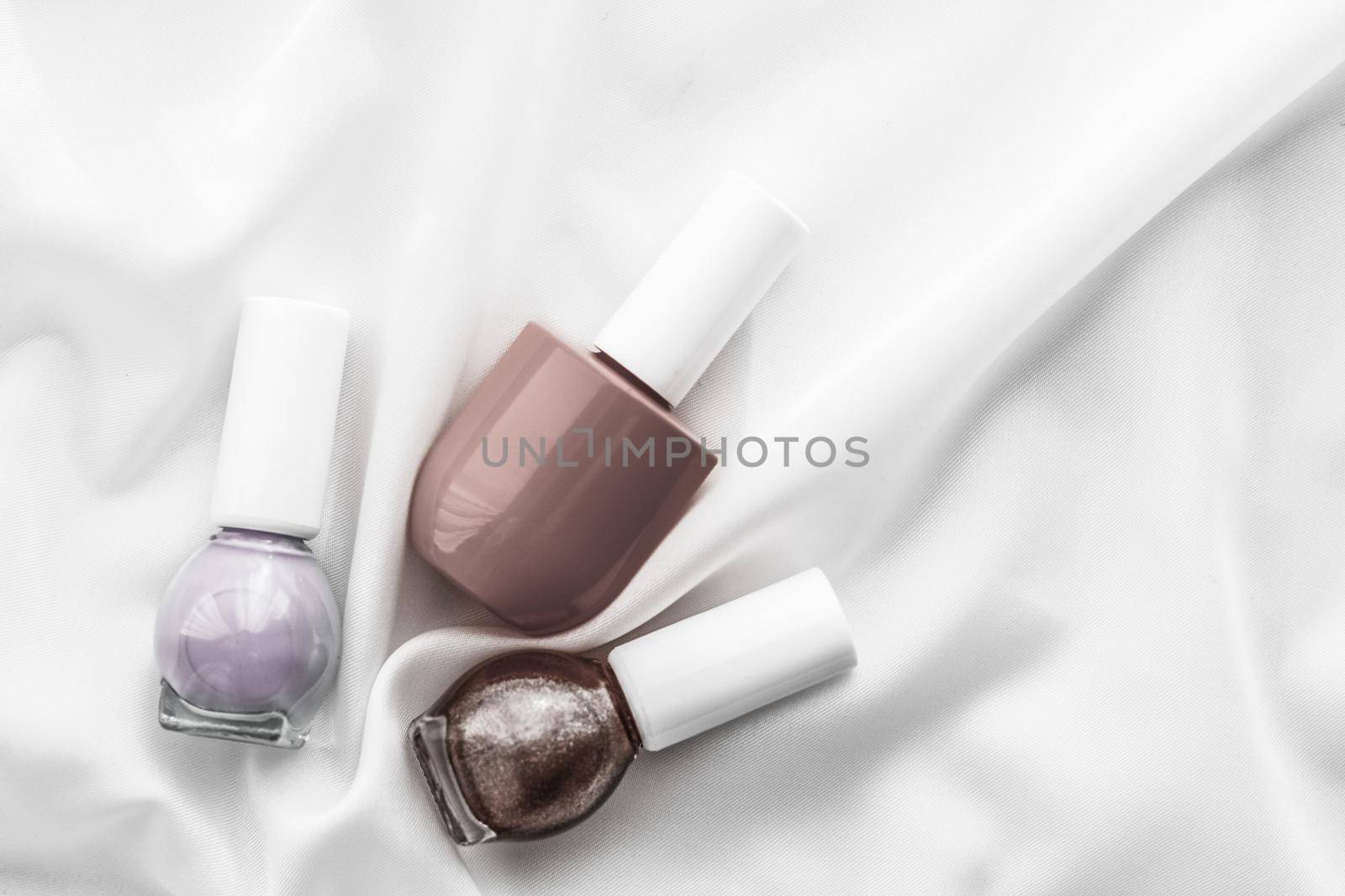 Cosmetic branding, salon and glamour concept - Nail polish bottles on silk background, french manicure products and nailpolish make-up cosmetics for luxury beauty brand and holiday flatlay art design