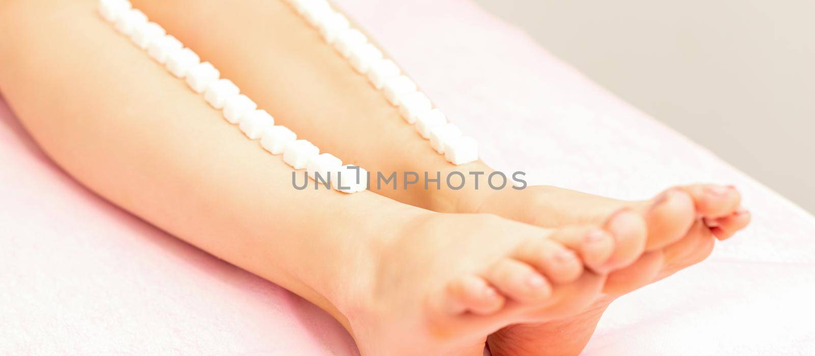 The concept of epilation, waxing. Sugar cubes lie down in a row on the naked white female leg