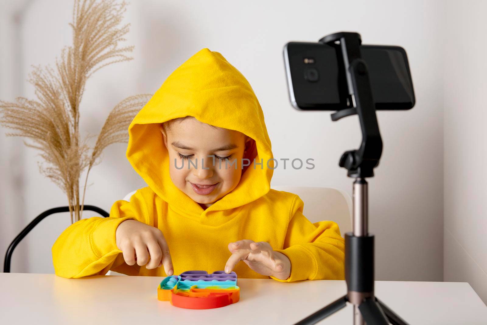 Adorable, cute, little boy blogger recording lifestyle blog, talking to camera of smartphone on tripod. Young influencer filming vlog for his channel. Child makes video for his followers online