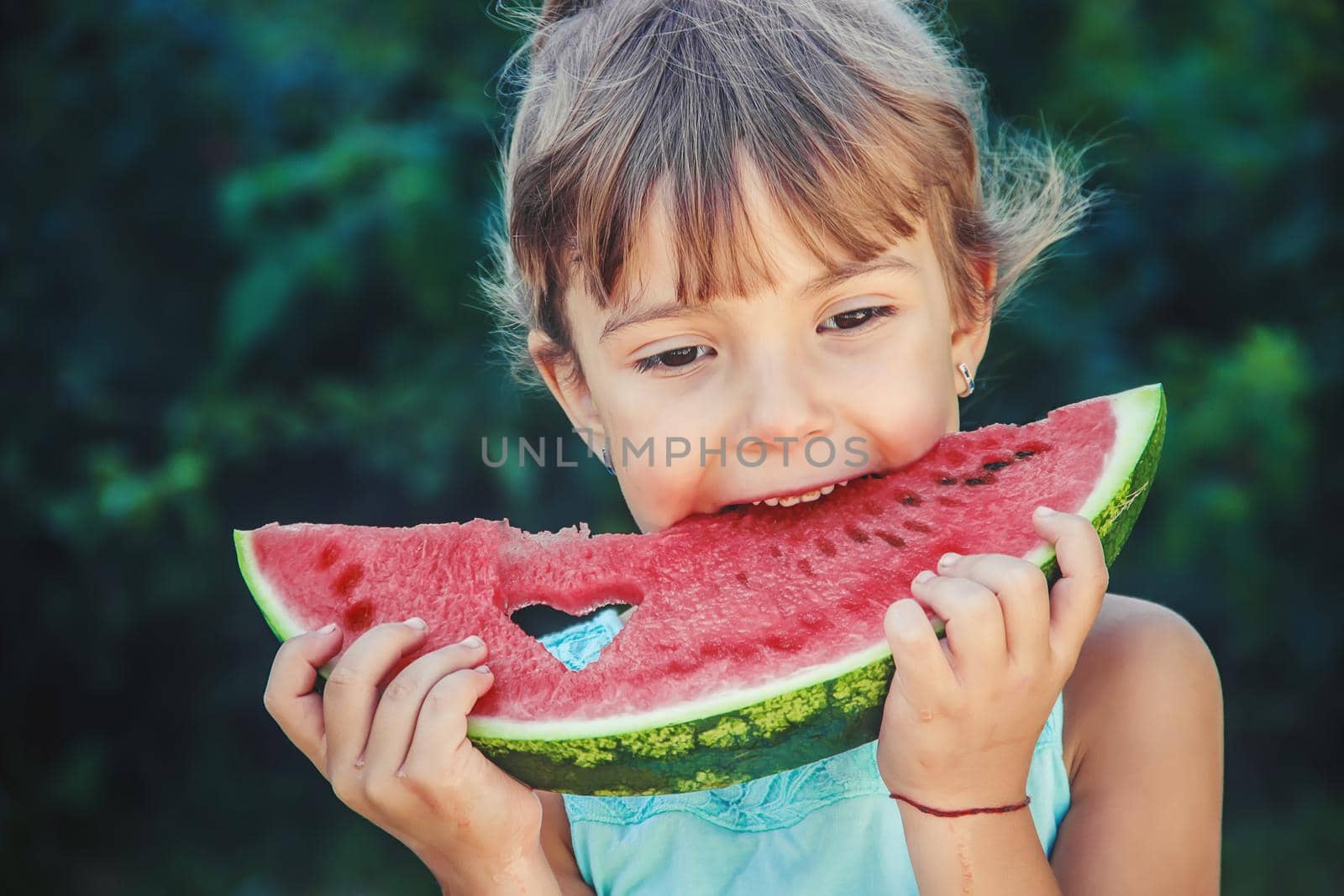 The child eats watermelon in summer. Selective focus. People.