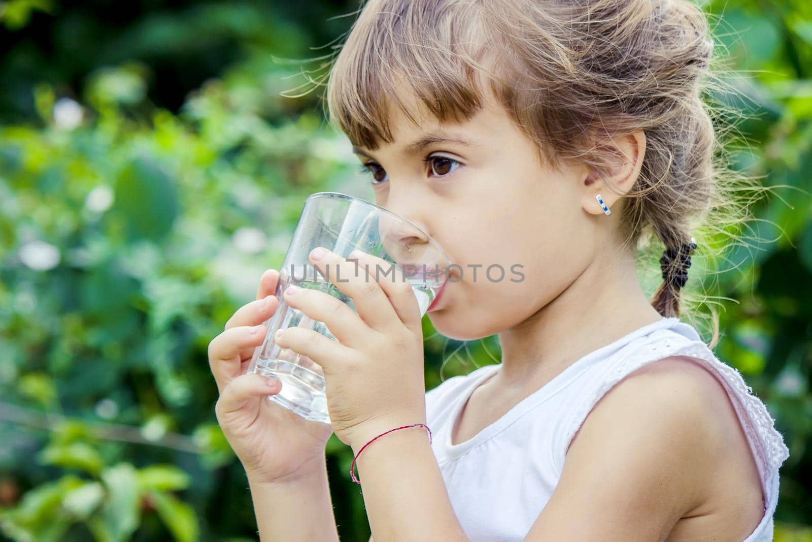 The child drinks clean water in summer. Selective focus. People.