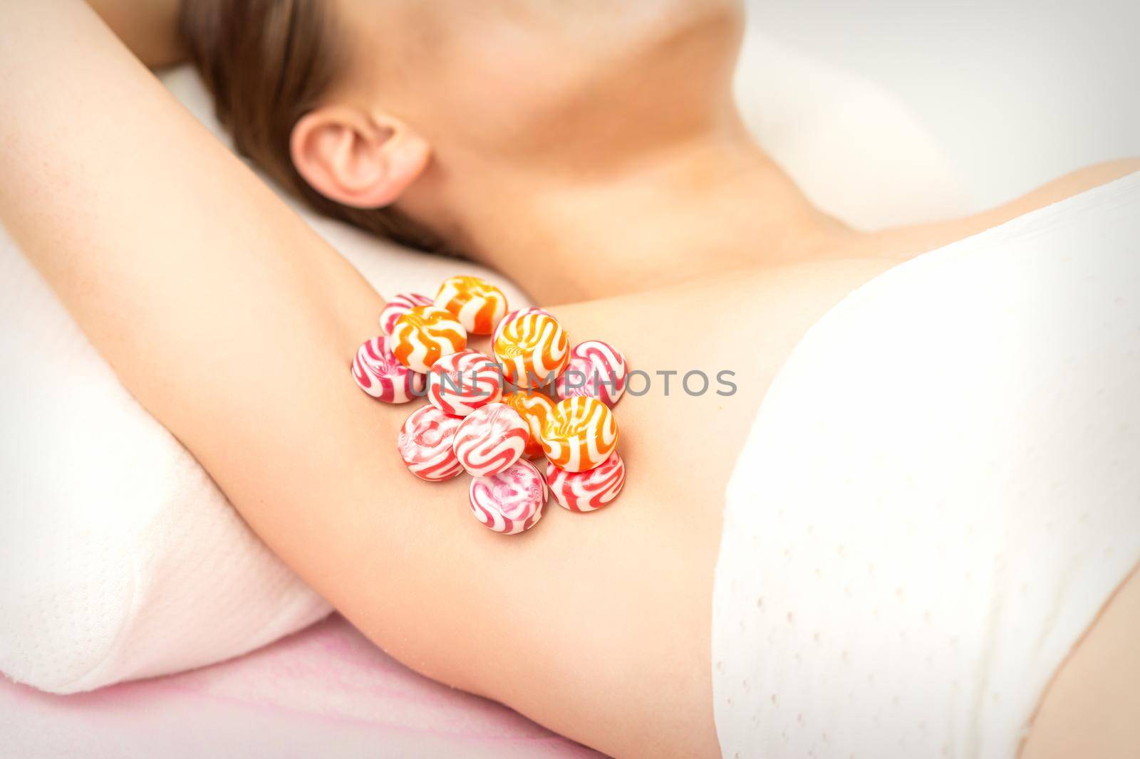 Waxing, depilation armpit concept. Colored round candies lying down on the female armpit, close up. by okskukuruza