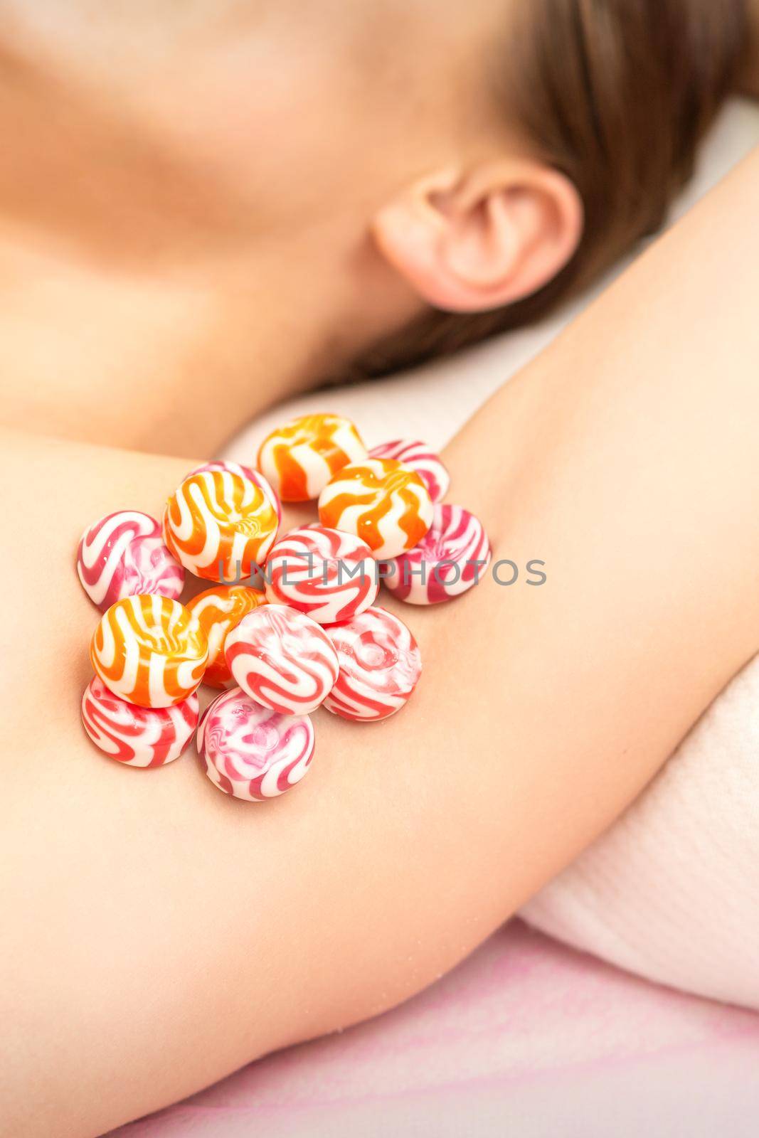 Waxing, depilation armpit concept. Colored round candies lying down on the female armpit, close up. by okskukuruza