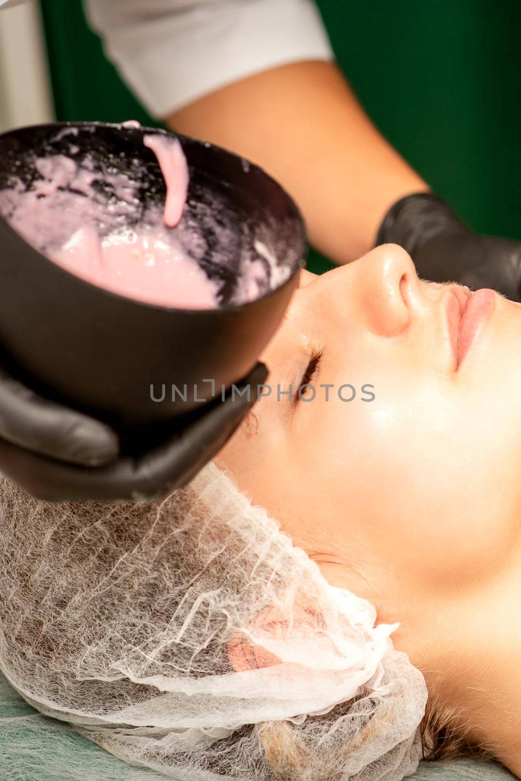 Beautiful young caucasian woman receiving an alginic mask to the face in beauty salon. Facial skin treatment