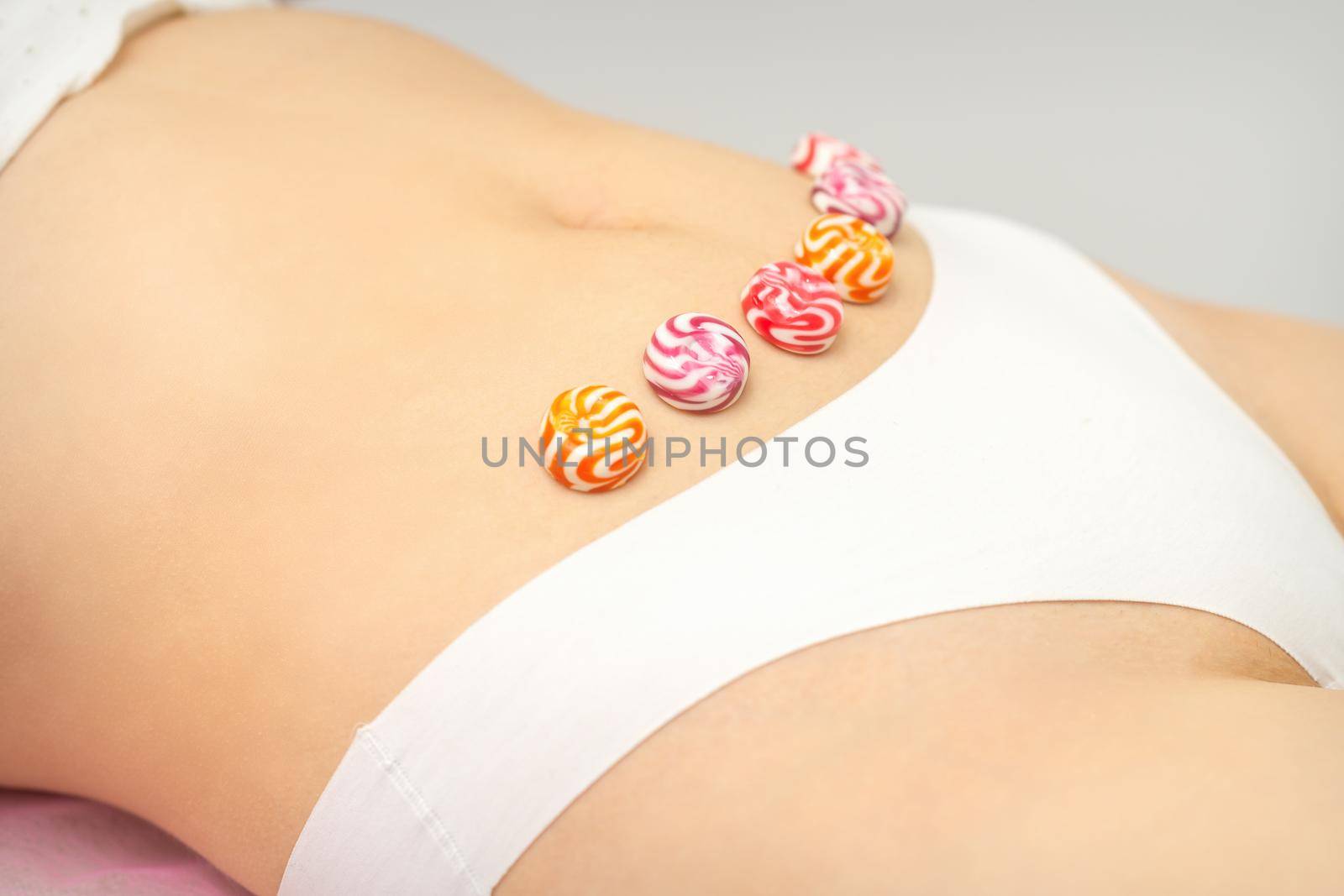 Concept of intimate depilation, intimate waxing, depilation. Round candies lying down in a row on the female bikini zone, intimate area, close up. by okskukuruza