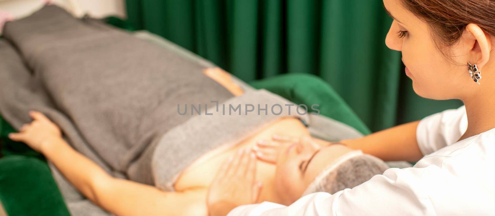 Massaging female breast, and shoulder. Beautician doing chest and shoulders massage of the young beautiful caucasian woman in beauty spa salon