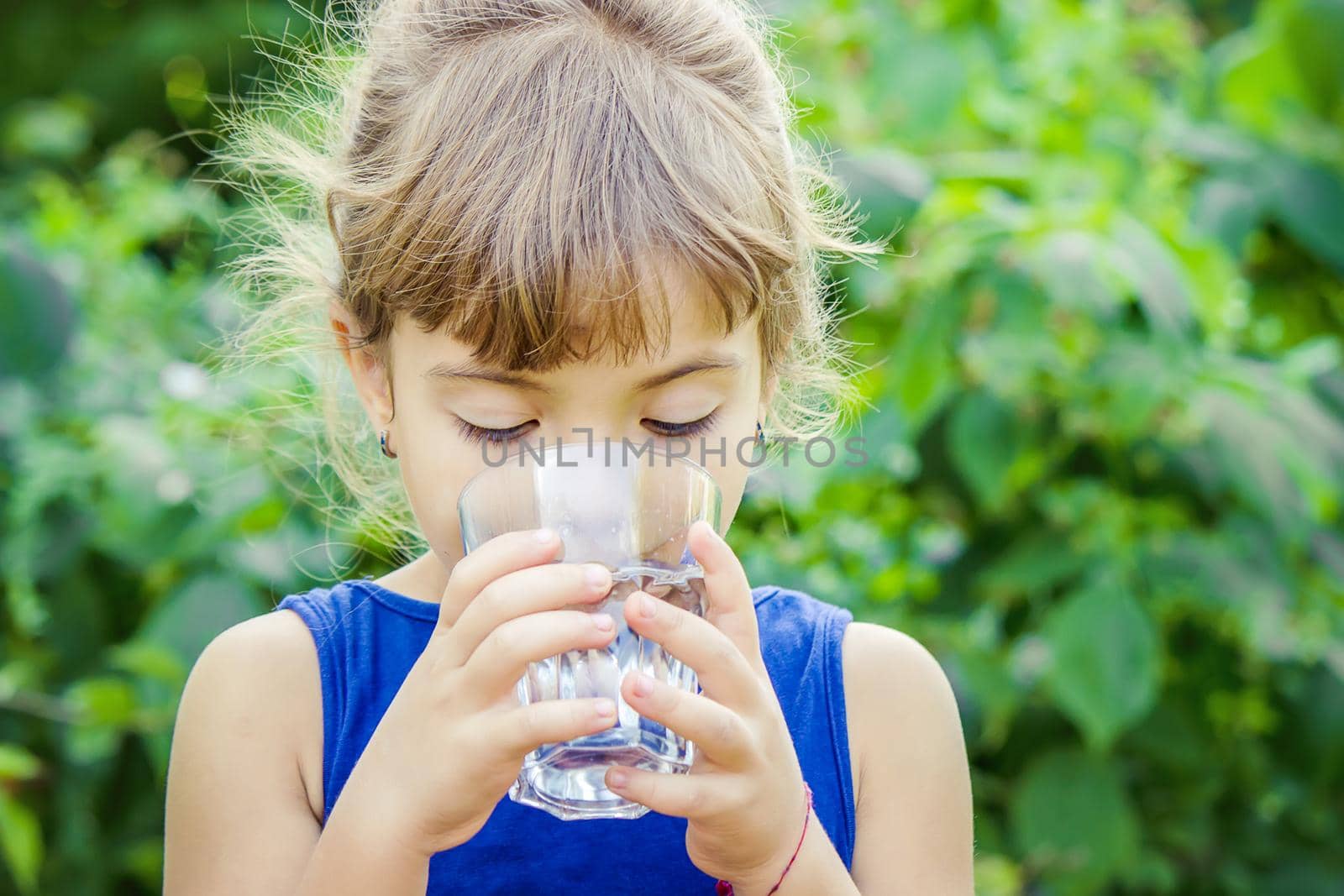 The child drinks clean water in summer. Selective focus. People.