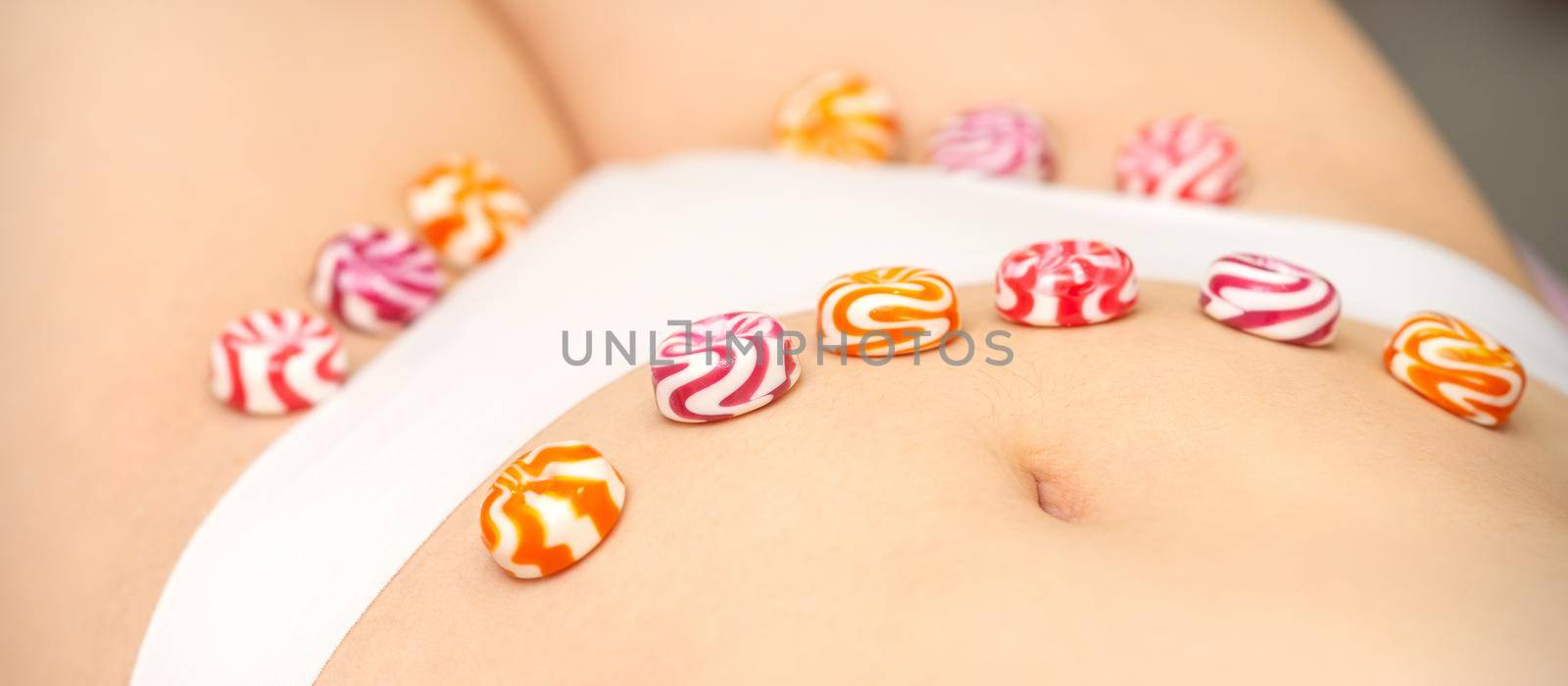 Concept of intimate depilation, intimate waxing, depilation. Round candies lying down in a row on the female bikini zone, intimate area, close up