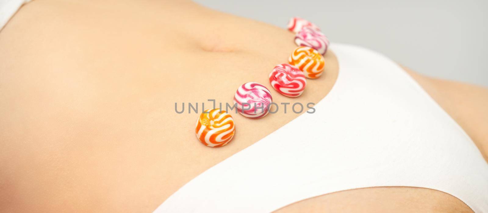 Concept of intimate depilation, intimate waxing, depilation. Round candies lying down in a row on the female bikini zone, intimate area, close up