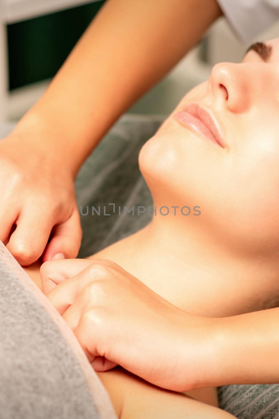 Massaging female breast, and shoulder. Young beautiful caucasian woman receiving chest and shoulders massage in beauty spa salon