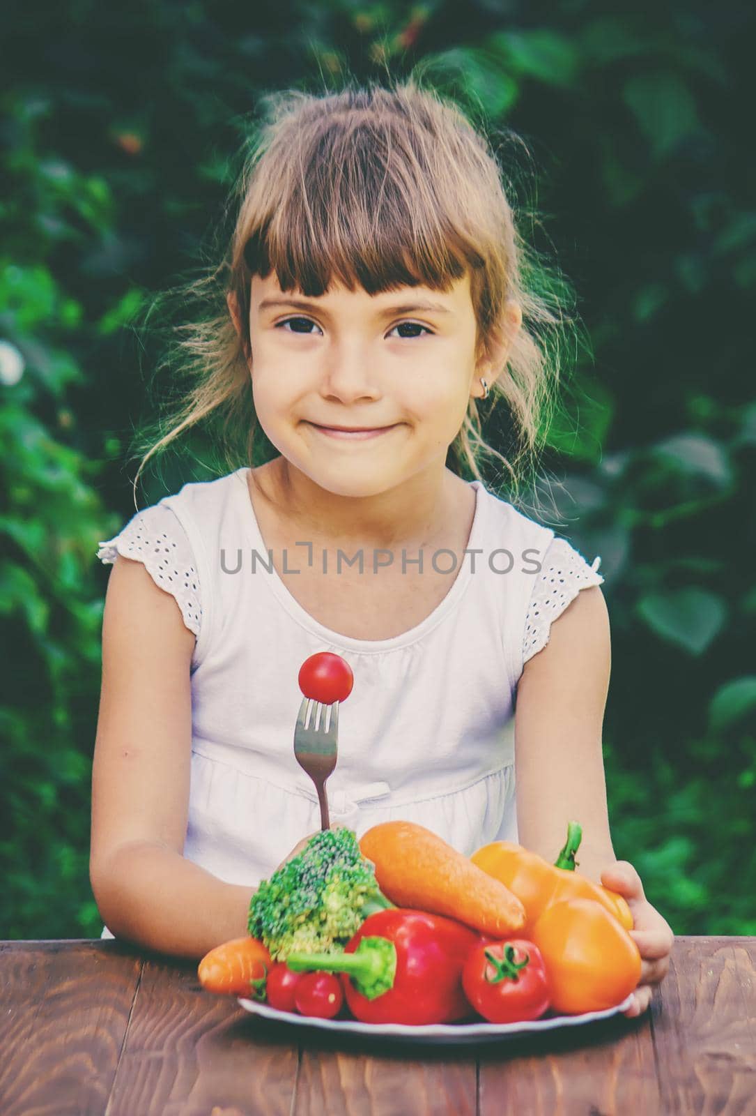 The child eats vegetables in summer. Selective focus. People.