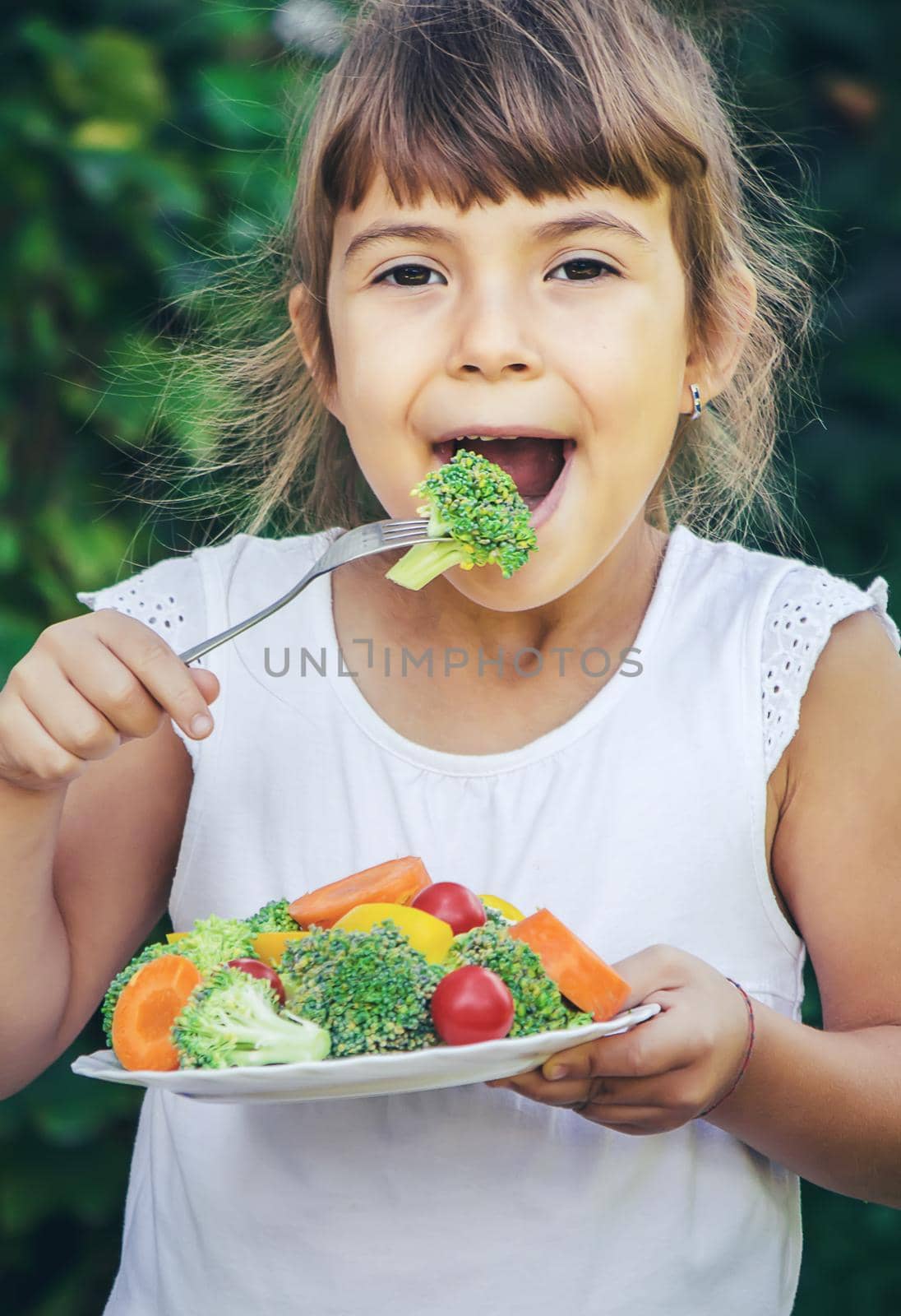 The child eats vegetables in summer. Selective focus. People.