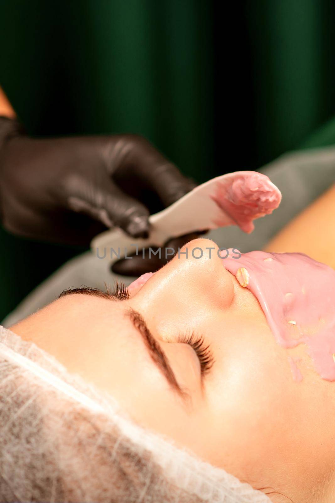 Beautiful young caucasian woman receiving an alginic mask to the face in beauty salon. Facial skin treatment